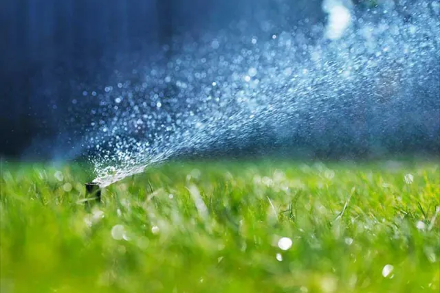 A sprinkler throwing a fine arc of water across turf.