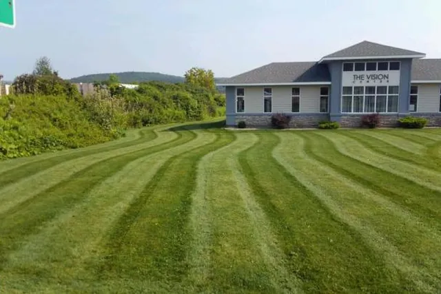 Wide commercial lawn cut into clean parallel stripes.