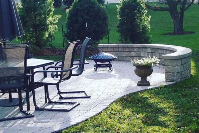 Stone patio with seating, a fire pit and a curved seat wall.