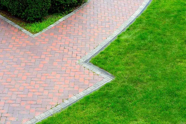 Herringbone paver walkway meeting a sharply edged lawn.