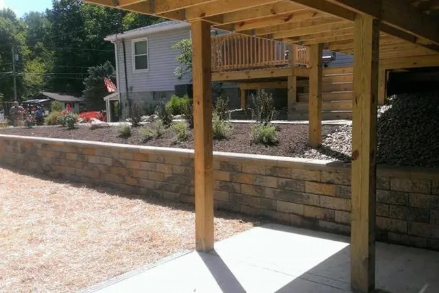 Retaining wall and gravel area beneath a timber pergola.